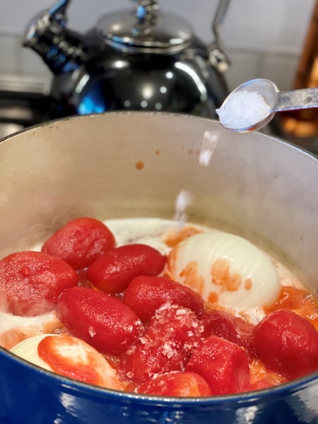 adding salt to tomatoes onion and butter