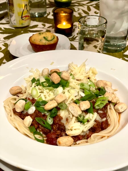 bowl of chili on spaghetti with toppings