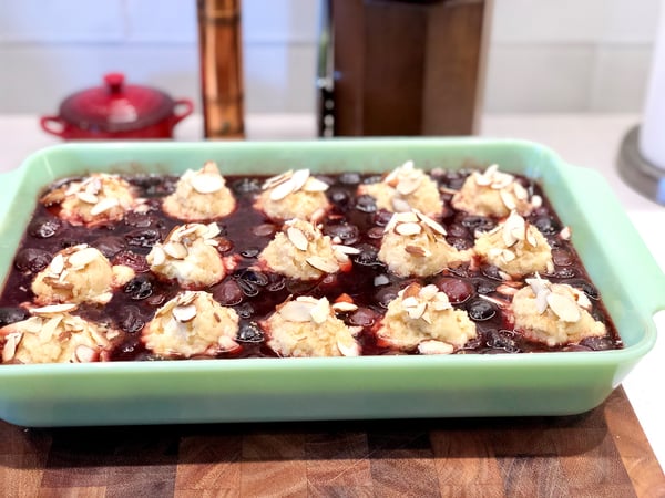 scooped biscuit topping on cherry filling with sliced almonds