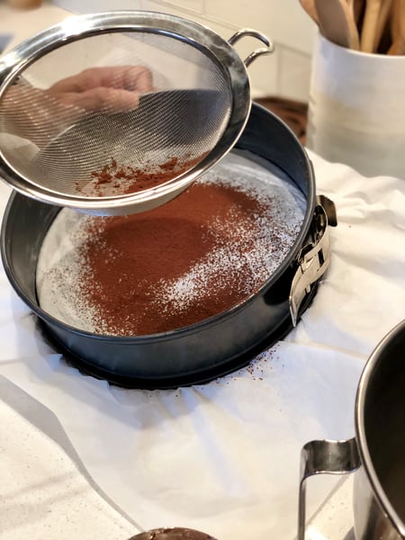 sifting cocoa powder to line the pan